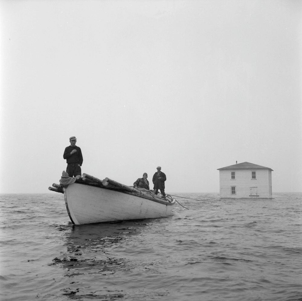 A house being floated from Silver Fox Island, Bonavista Bay, to Dover, Newfoundland, 1961
