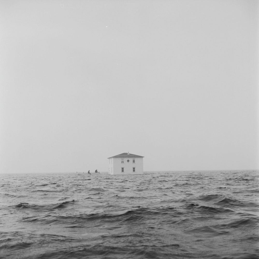 A house being towed by motorboat from Fox Island to Flat Island, Dover, Newfoundland, 1961